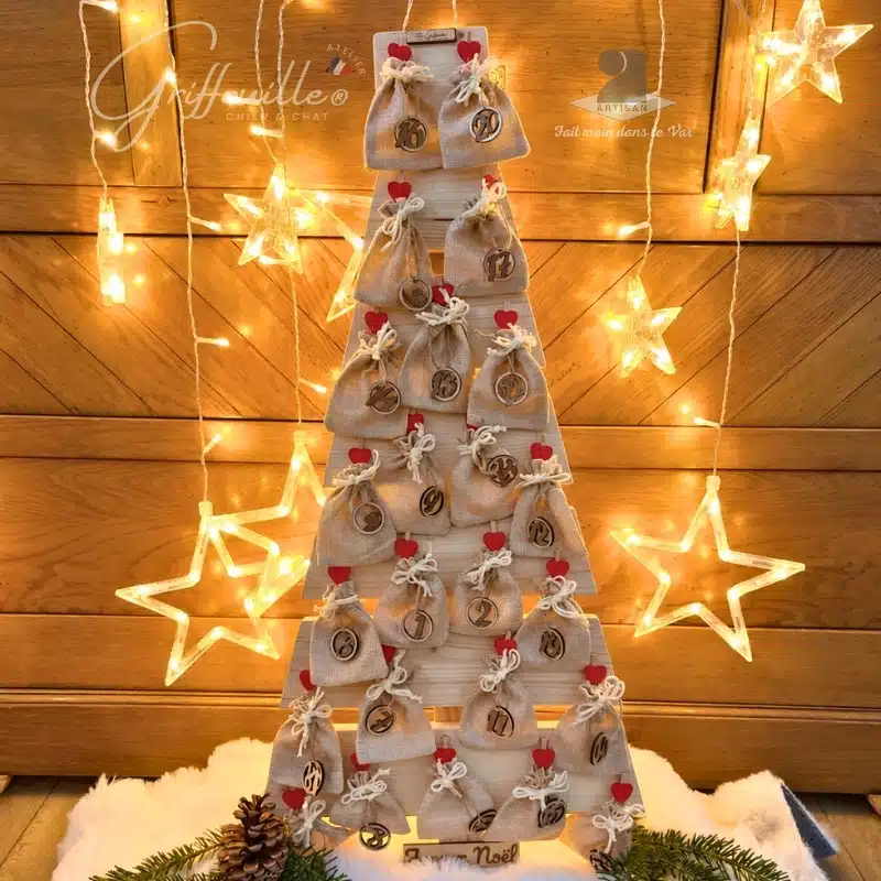 Calendrier de l'Avent en bois en forme de sapin avec petits sacs en jute, présenté comme décoration de Noël